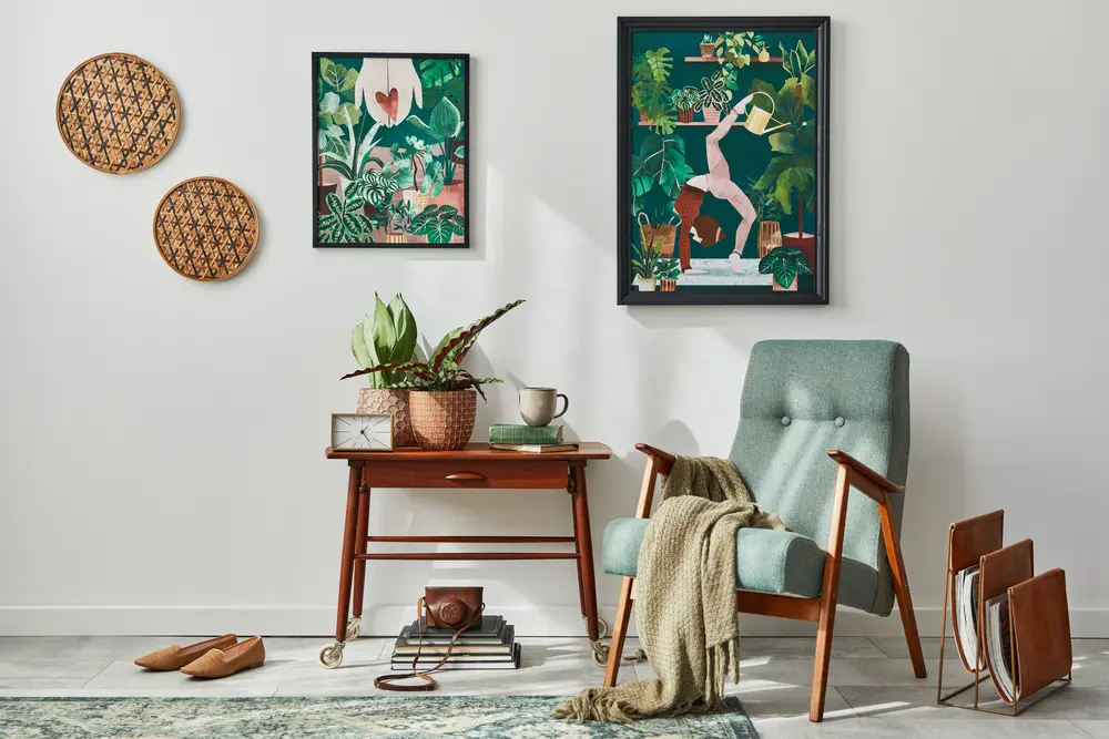 Salon de style moderne du milieu du siècle avec un bureau en bois et une chaise turquoise. Les murs sont ornés d'imprimés botaniques aux couleurs vives. Des paniers tressés et une plante en pot apportent une touche chaleureuse.