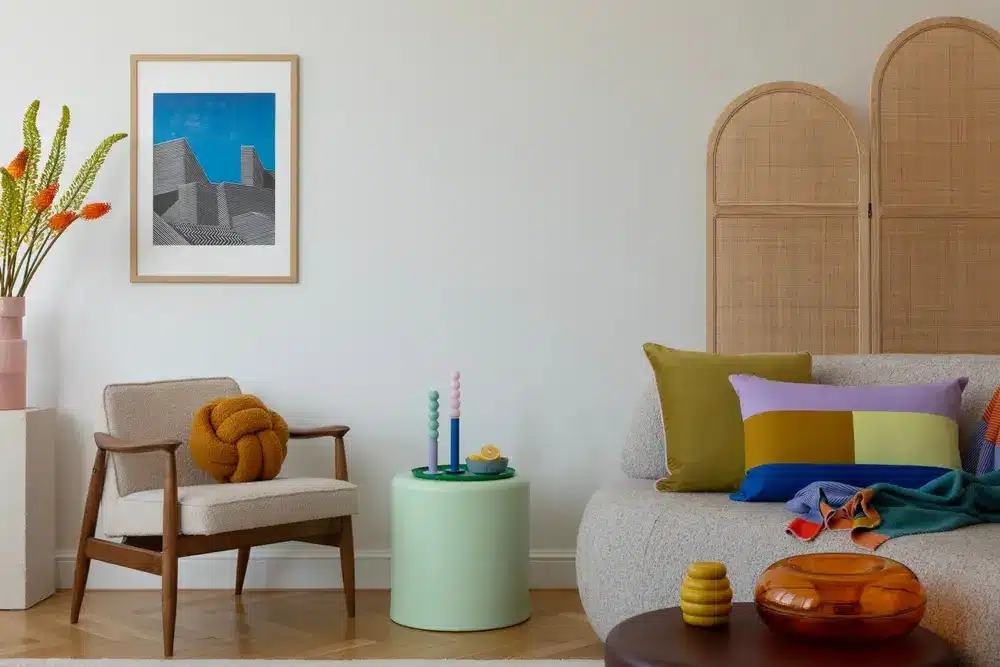 Salon élégant avec fauteuil beige, coussin jaune à nœuds, art mural abstrait et décoration colorée. Ambiance chaleureuse avec une touche de modernité et de couleur.